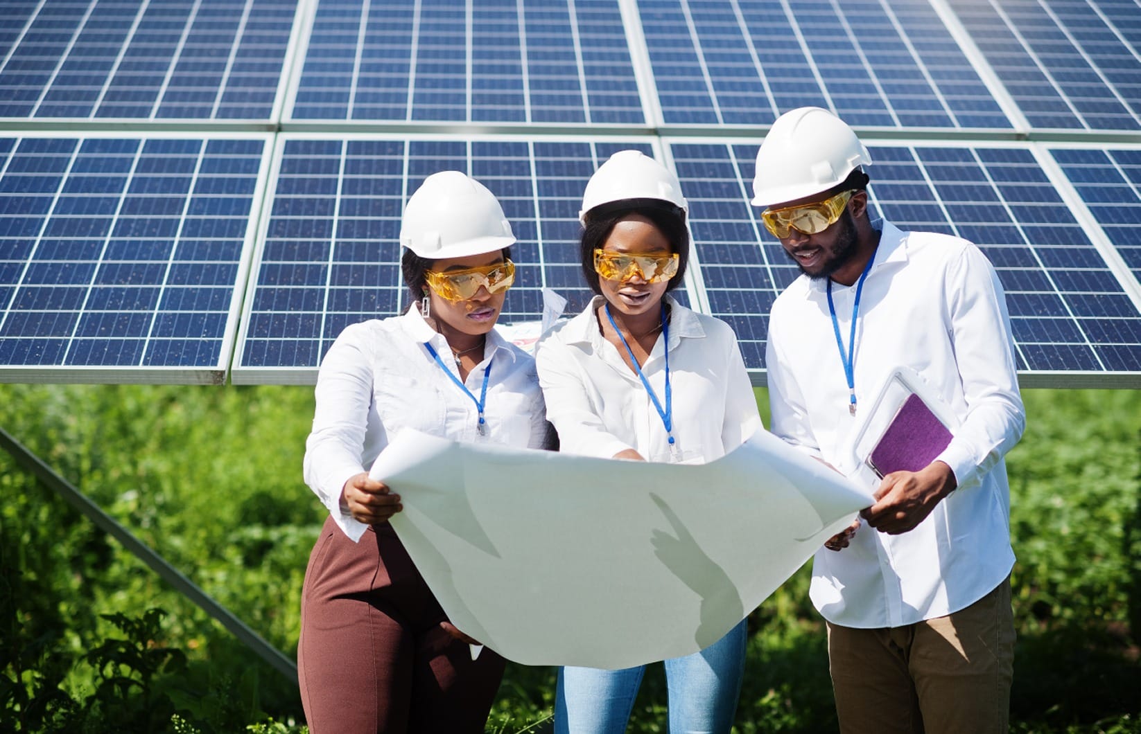 Engineers reviewing plans in front of solar panels